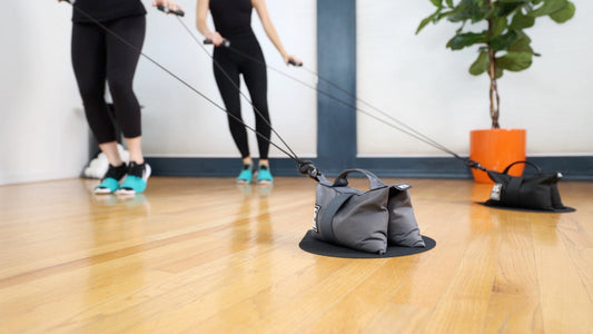 Two people working out together in a studio using HupSix, showing its compact and social design for small-space cardio.