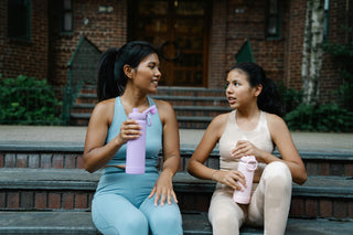 Mom and daughter hanging out after a HupSix workout at home, smiling and relaxed.